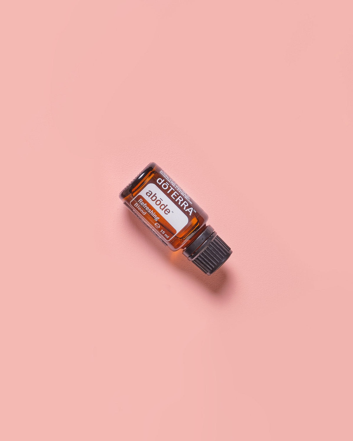 Abōde mélange d'huiles essentielles dōTERRA, flacon sur fond rose poudré