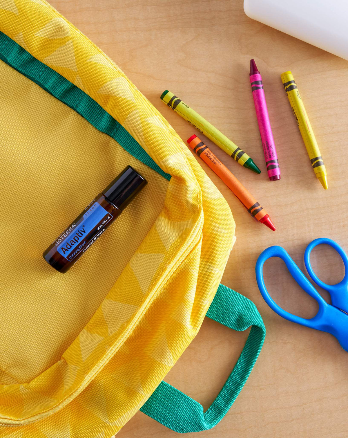 Adaptiv Touch mélange en applicateur à bille dōTERRA, roll-on sur un cartable jaune avec des crayons