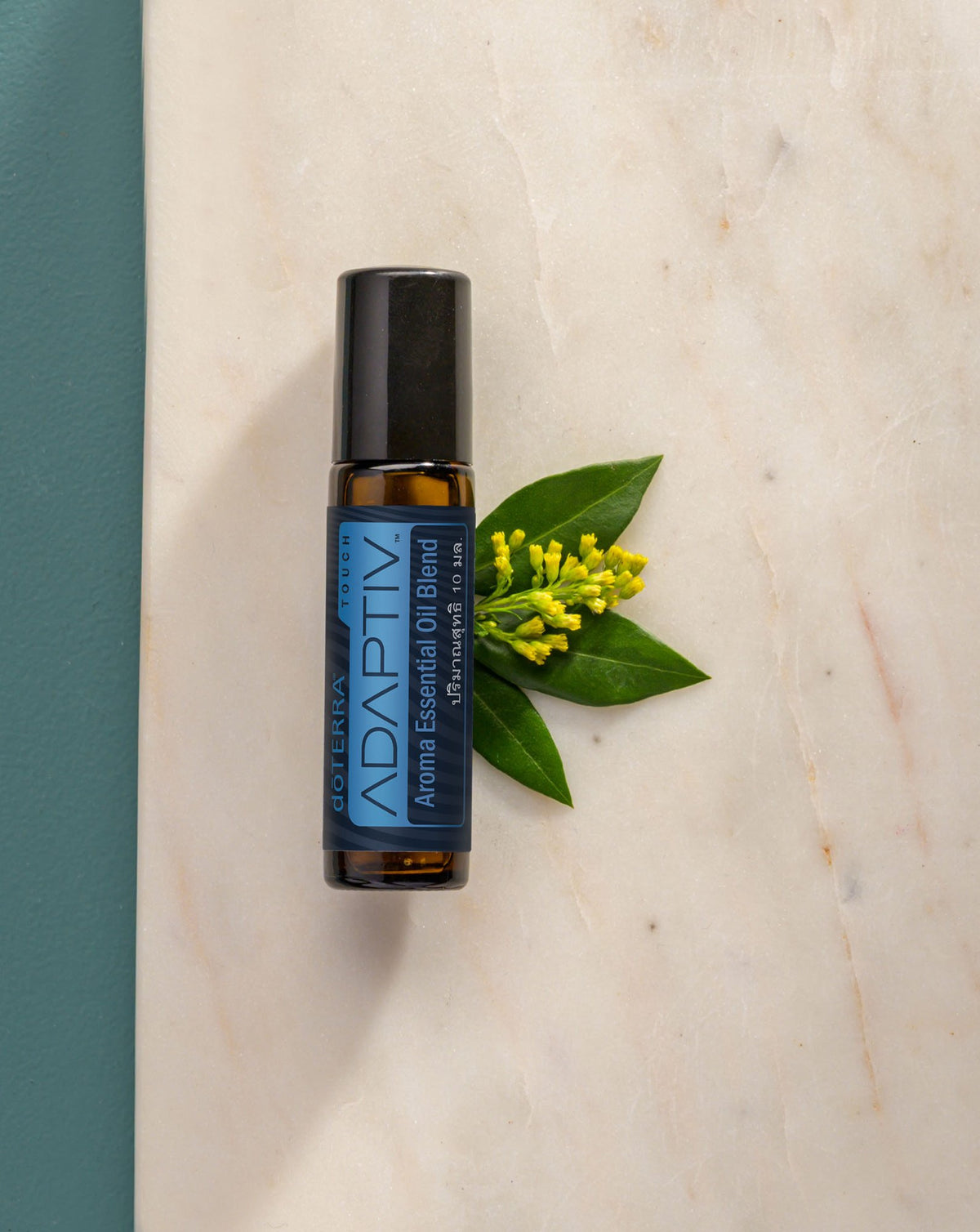 Adaptiv Touch mélange en applicateur à bille dōTERRA, roll-on sur du marbre avec des fleurs jaunes