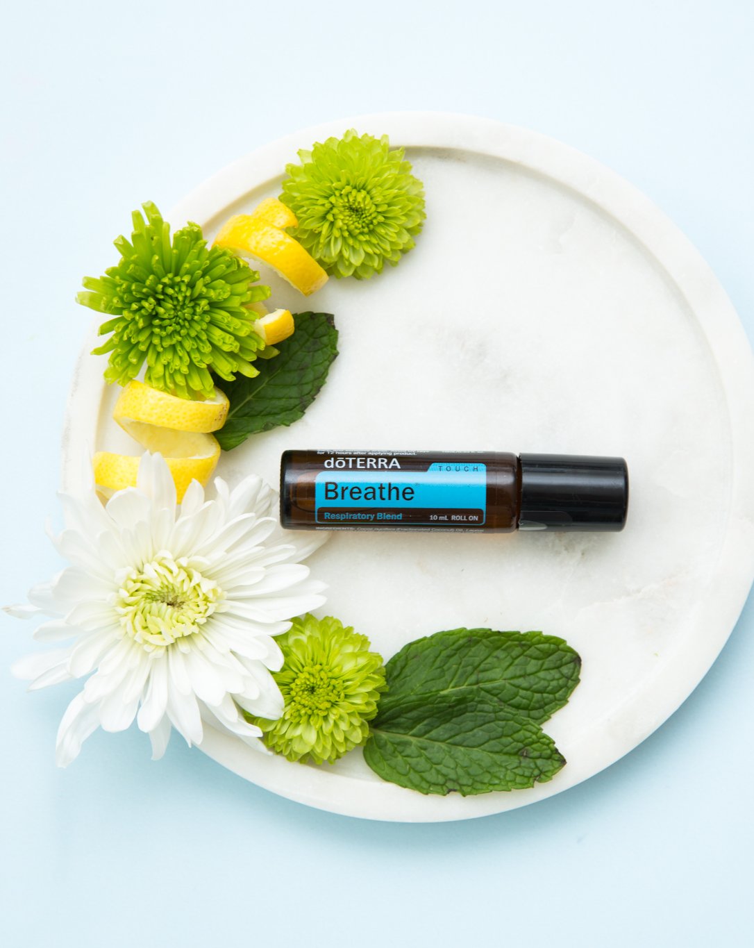 Air Touch mélange en applicateur à bille dōTERRA, roll-on sur un plateau avec fleurs et menthe