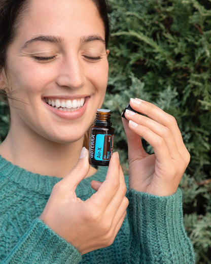 Air-X mélange d'huiles essentielles dōTERRA, flacon tenu par une femme souriante