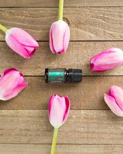 Align mélange d'huiles essentielles dōTERRA, flacon parmi des tulipes roses