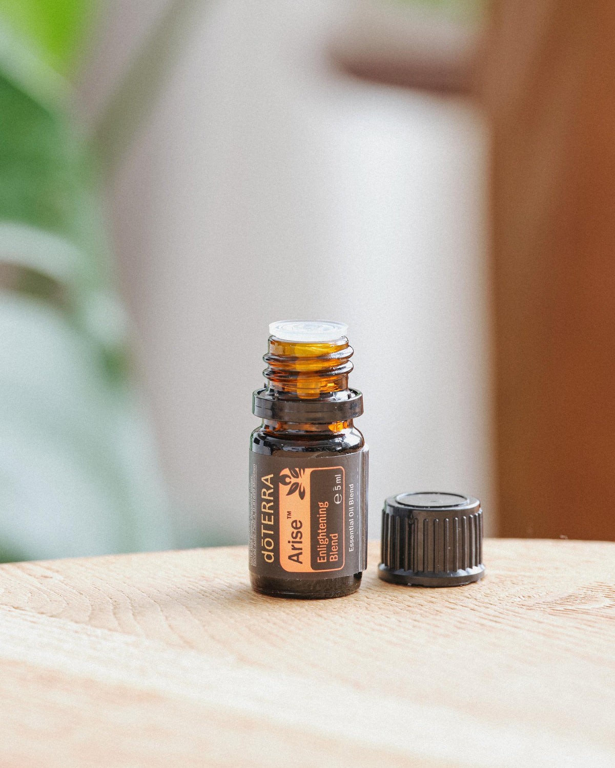 Arise mélange d'huiles essentielles dōTERRA, flacon sur une table en bois