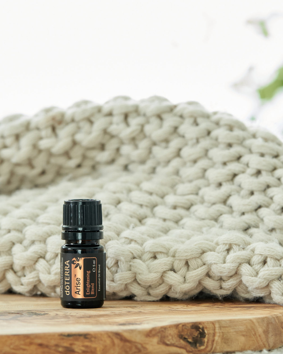 Arise mélange d'huiles essentielles dōTERRA, flacon sur un plaid tricoté