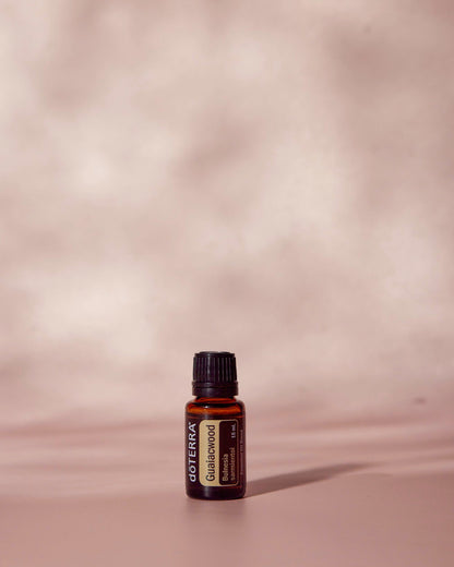 Bois de gaïac huile essentielle dōTERRA, sur fond rose poudré