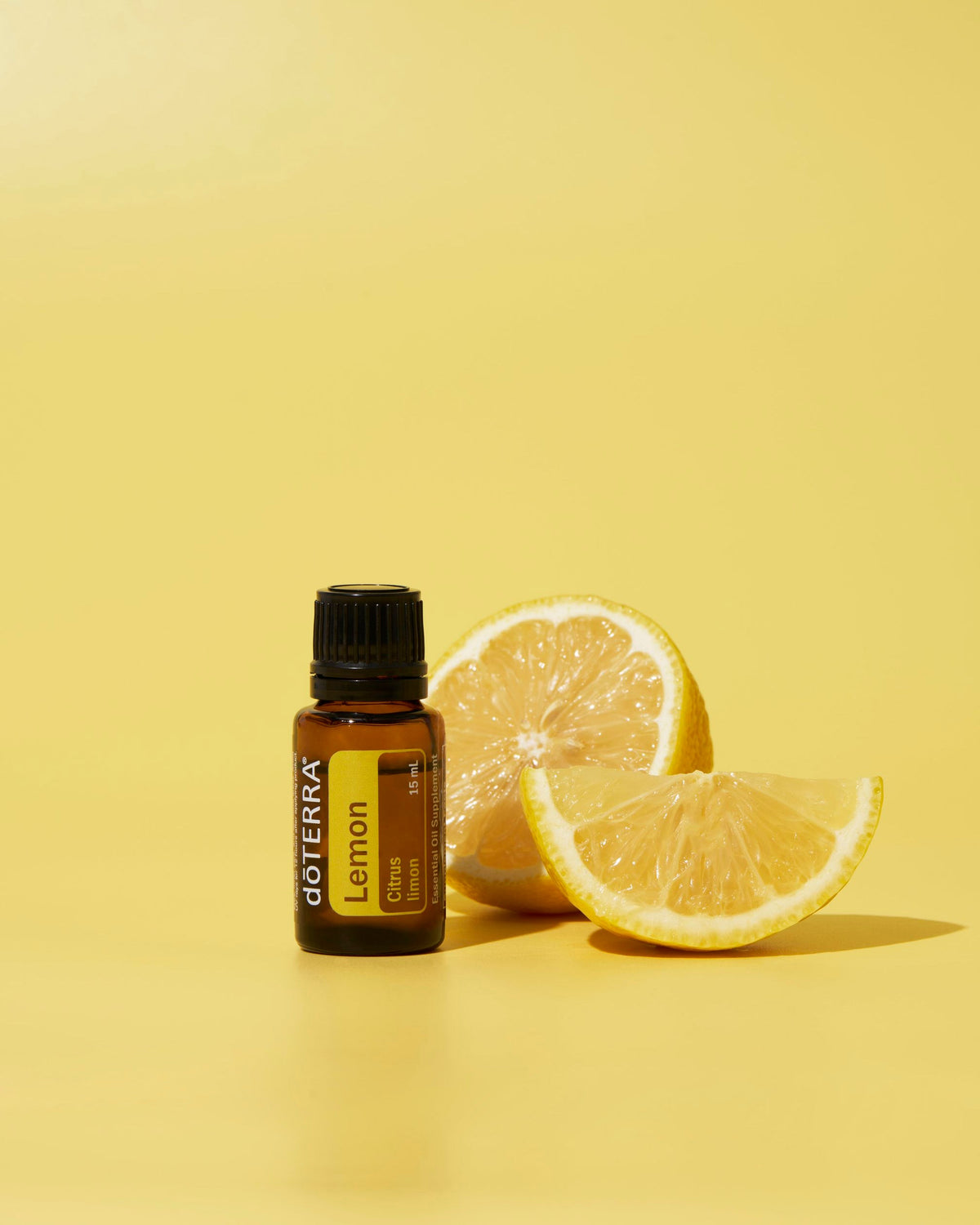 Citron huile essentielle dōTERRA, avec des citrons coupés sur fond jaune