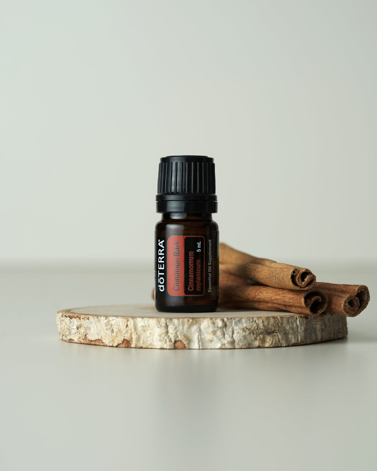 Écorce de cannelle huile essentielle dōTERRA, sur une rondelle de bois avec des bâtons de cannelle
