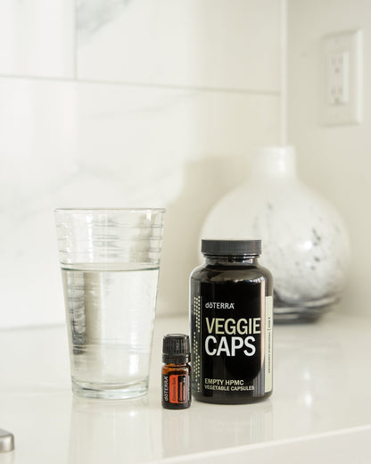 Écorce de cannelle huile essentielle dōTERRA, avec un pot de gélules et un verre d'eau