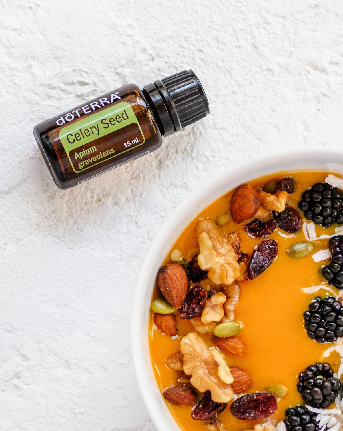 Graines de céleri huile essentielle dōTERRA, flacon et bol de smoothie aux fruits secs
