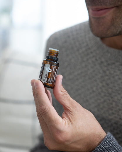Hygge mélange d'huiles essentielles dōTERRA, flacon tenu en main