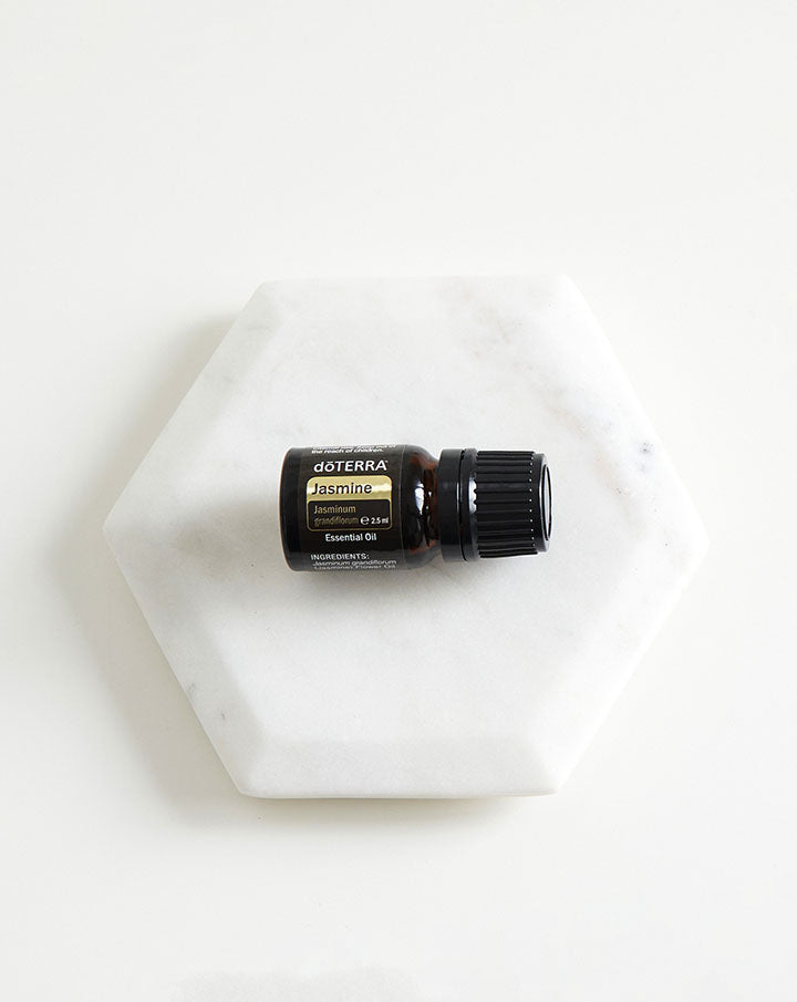 Flacon d'huile essentielle de Jasmin dōTERRA posé sur un socle en marbre blanc