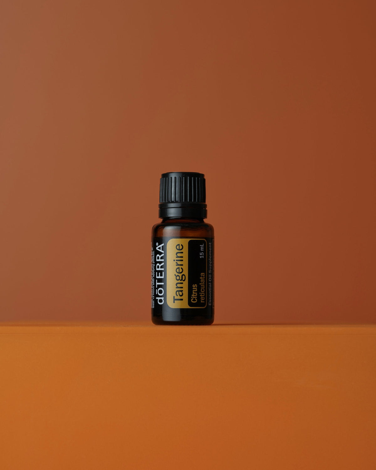 Mandarine huile essentielle dōTERRA, sur fond terracotta