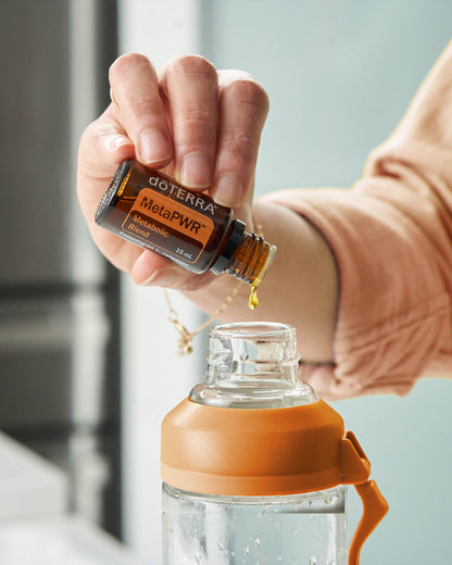MetaPWR mélange d'huiles essentielles dōTERRA, flacon versé dans un verre