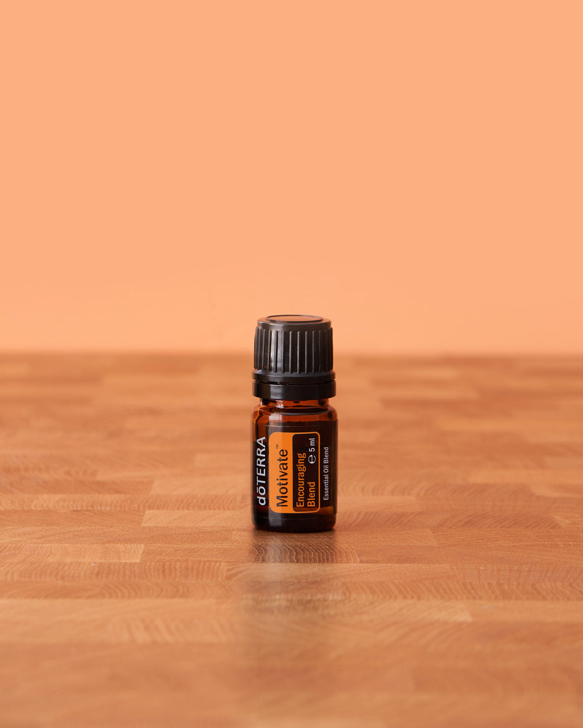 Motivate mélange d'huiles essentielles dōTERRA, flacon sur fond pêche