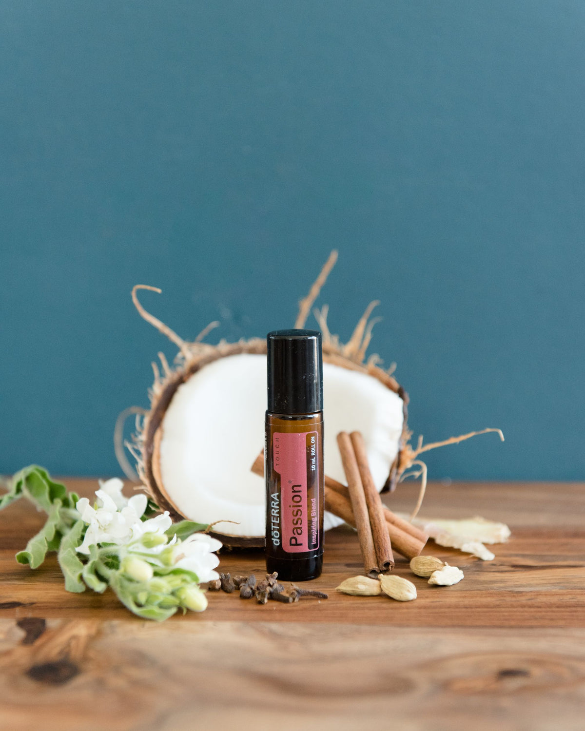 Passion mélange d'huiles essentielles dōTERRA, flacon avec fleurs séchées sur fond bleu-vert