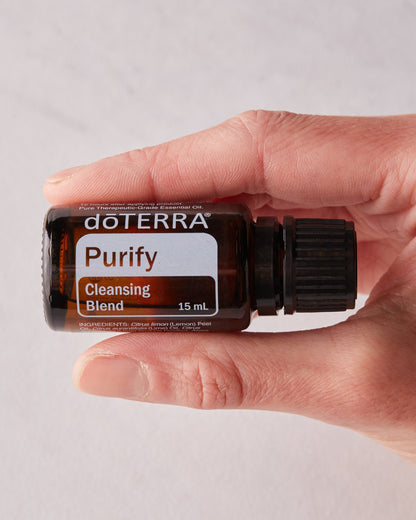 Purify mélange d'huiles essentielles dōTERRA, flacon tenu en main