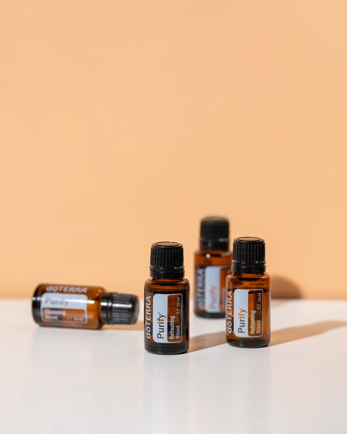 Purify mélange d'huiles essentielles dōTERRA, flacons sur fond pêche