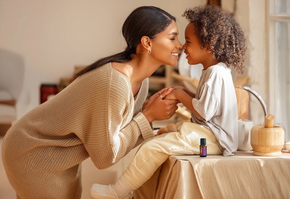 Une mère et son enfant se sourient nez à nez, un flacon dōTERRA posé sur la table