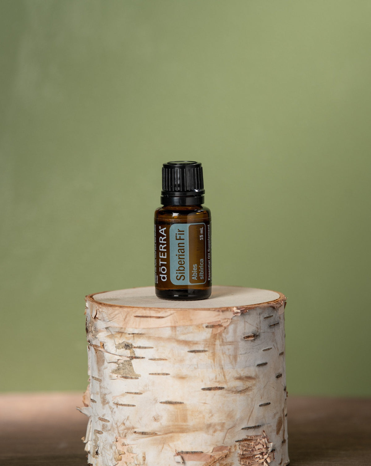 Sapin de Sibérie huile essentielle dōTERRA, flacon sur une bûche de bouleau