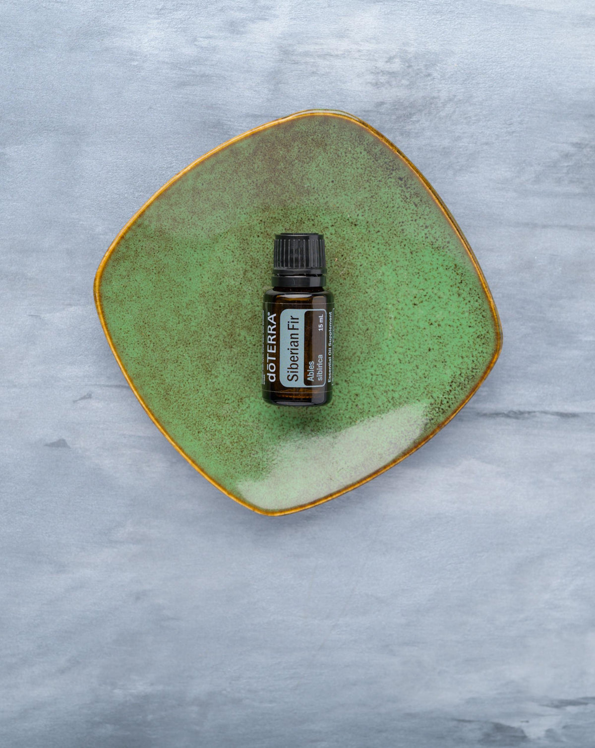 Sapin de Sibérie huile essentielle dōTERRA, flacon sur une coupelle en céramique verte
