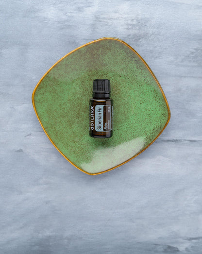 Sapin de Sibérie huile essentielle dōTERRA, flacon sur une coupelle en céramique verte