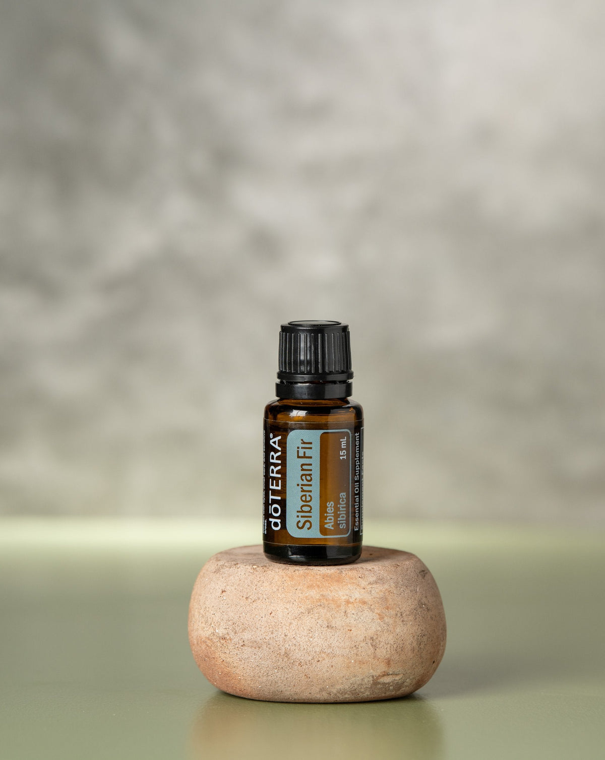Sapin de Sibérie huile essentielle dōTERRA, flacon sur un galet