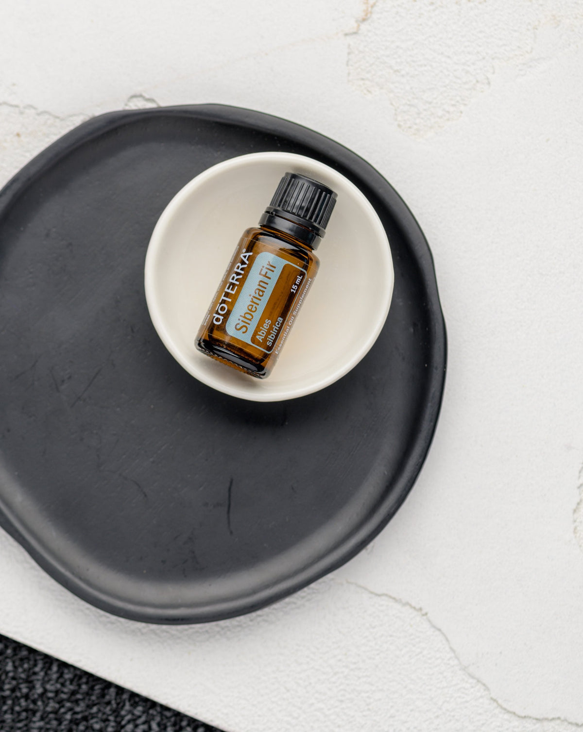 Sapin de Sibérie huile essentielle dōTERRA, flacon dans une coupelle sur un plateau noir