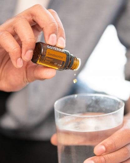 Zendocrine mélange d'huiles essentielles dōTERRA, flacon versé dans un verre d'eau